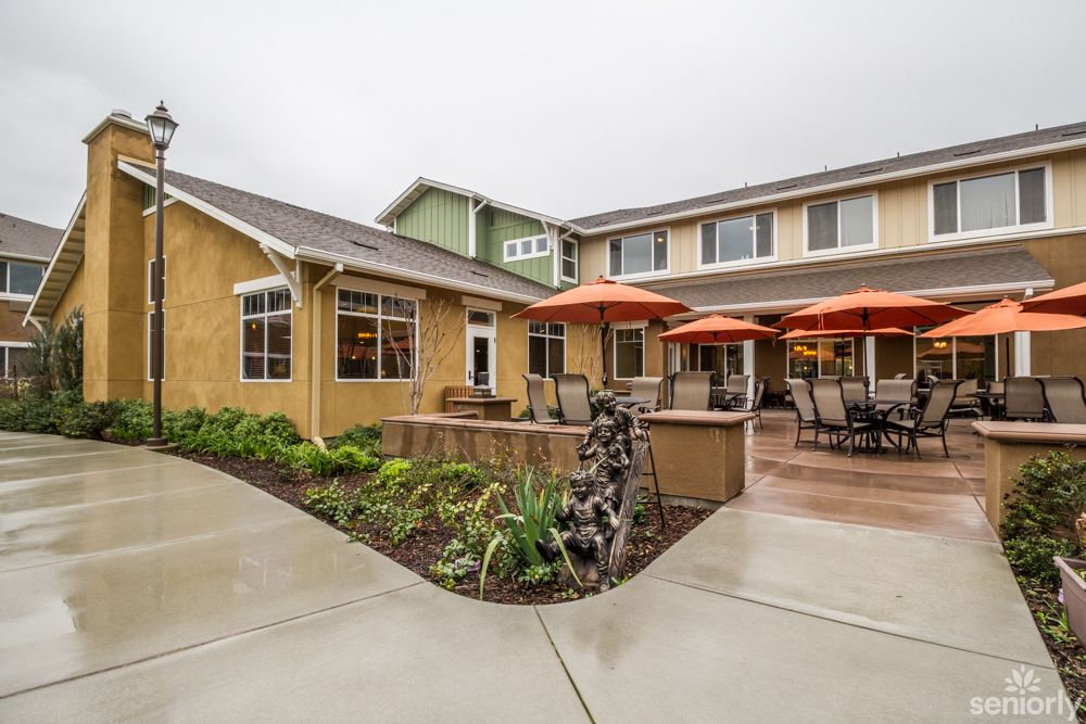 A modern house with a furnished patio area featuring orange umbrellas and seating.