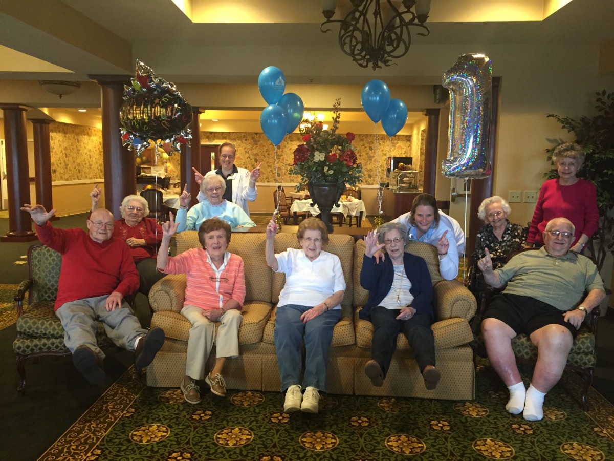 A group of seniors celebrating with balloons in a cozy living room setting.