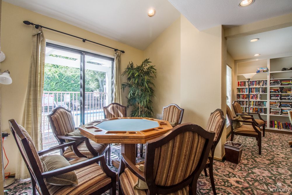 A cozy dining area with a round table and striped chairs, illuminated by natural light from the sliding glass doors.