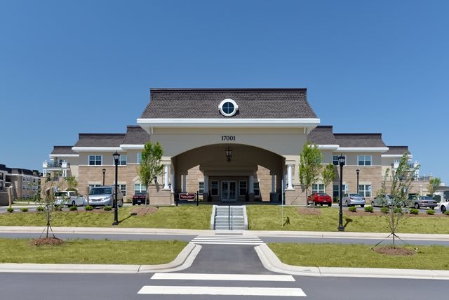 A modern hospital building with an arched entrance and clear blue sky.