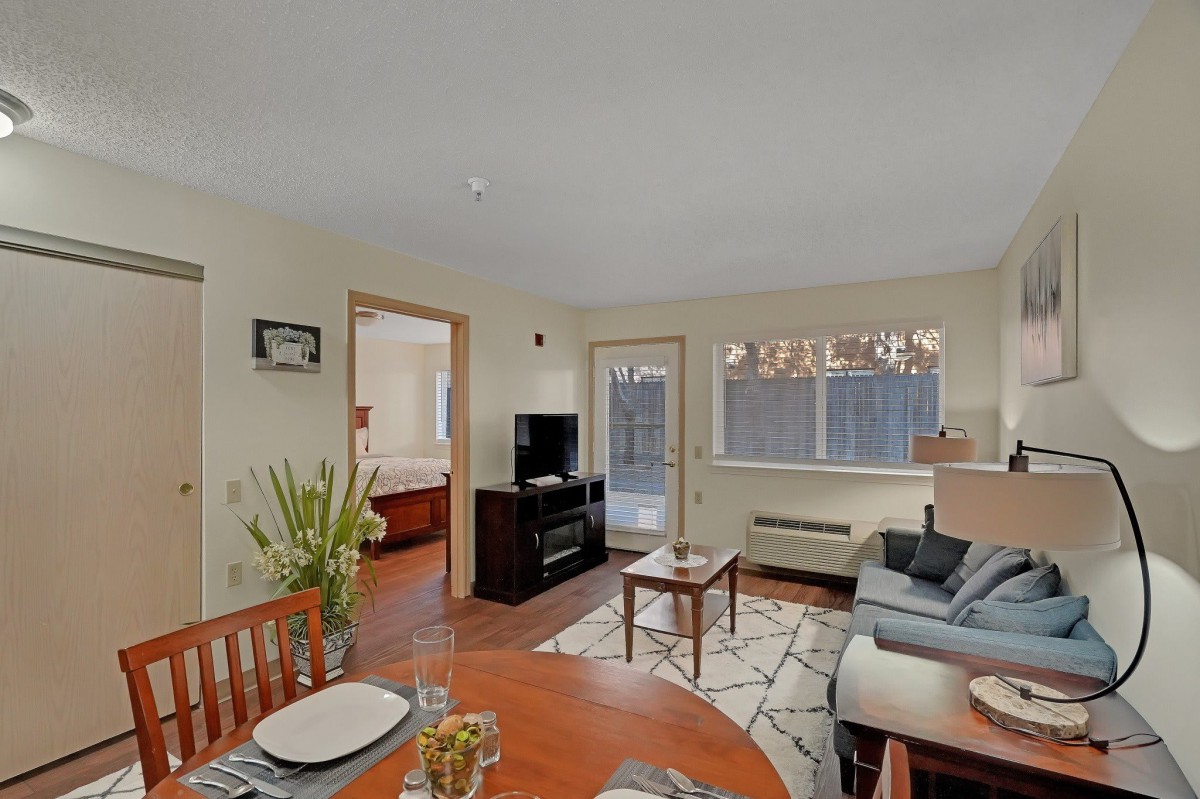 A cozy living room with a sofa, TV, dining table, and large window.