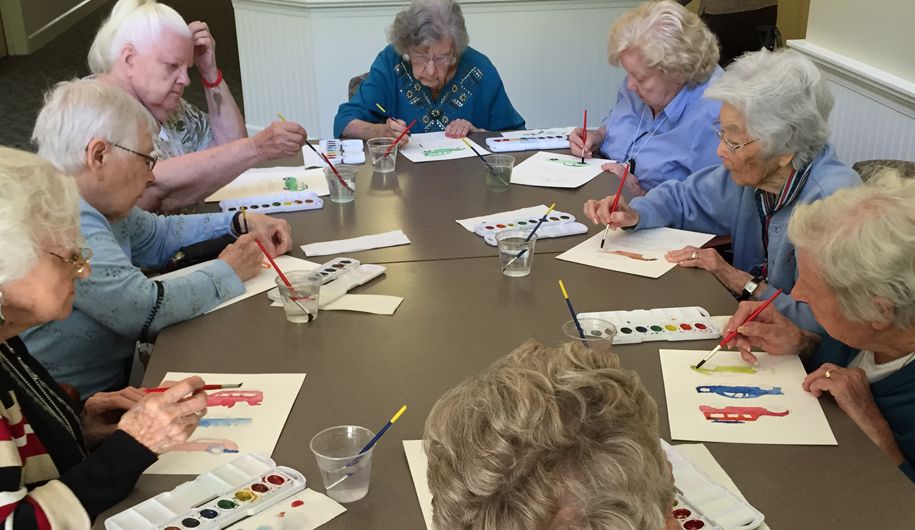 A group of elderly individuals engaged in a watercolor painting activity.