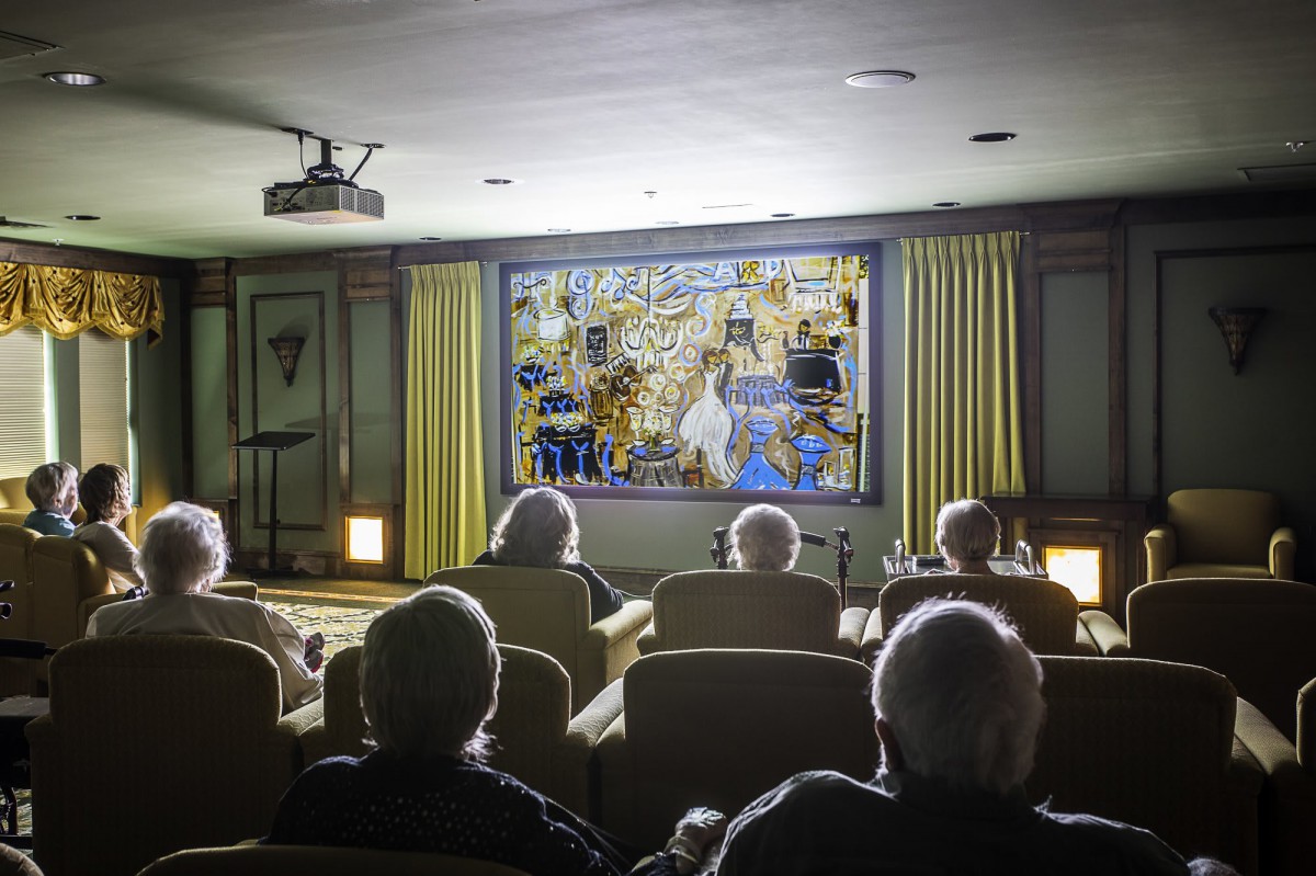 A group of seniors watching a movie in a small theater.