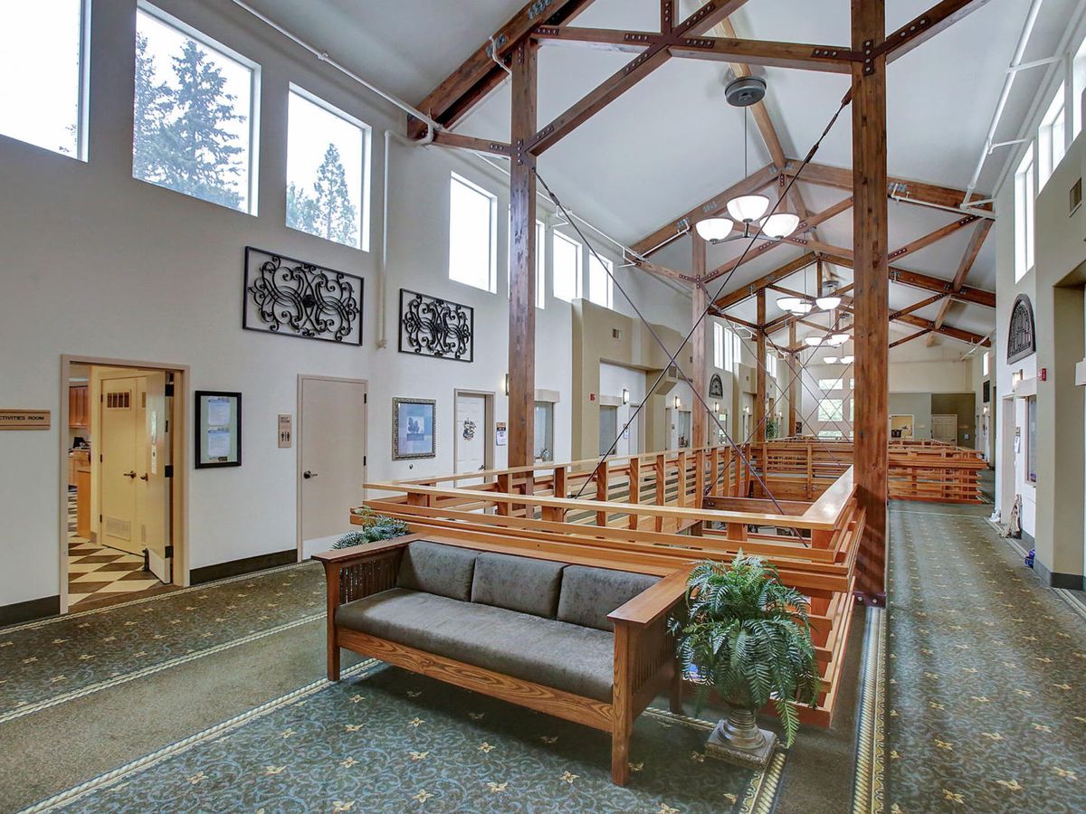 A spacious and well-lit lobby area featuring wooden beams, comfortable seating, and large windows.