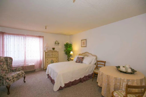 A cozy and well-furnished bedroom featuring a double bed, bedside table, and a window with soft curtains.