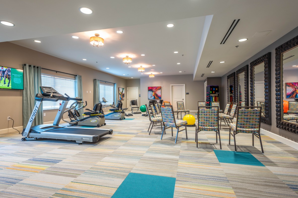 A modern gym equipped with treadmills, exercise machines, and seating in a well-lit indoor space.