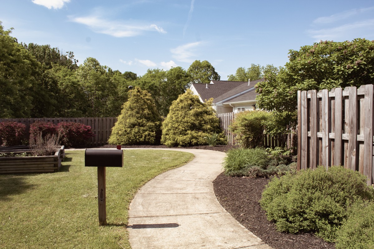 A beautifully landscaped garden with a winding pathway, surrounded by lush greenery and trees.