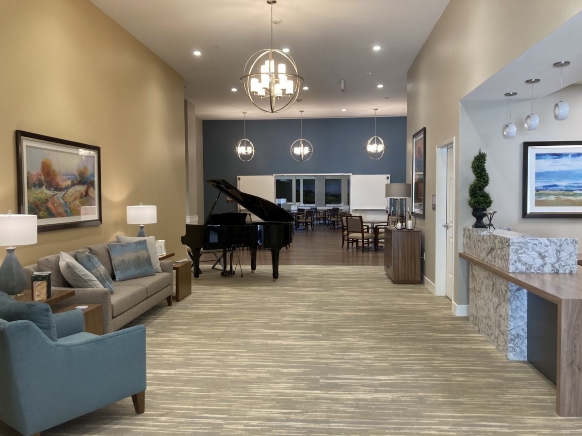 A modern interior living space featuring a grand piano, comfortable seating, and elegant chandeliers.
