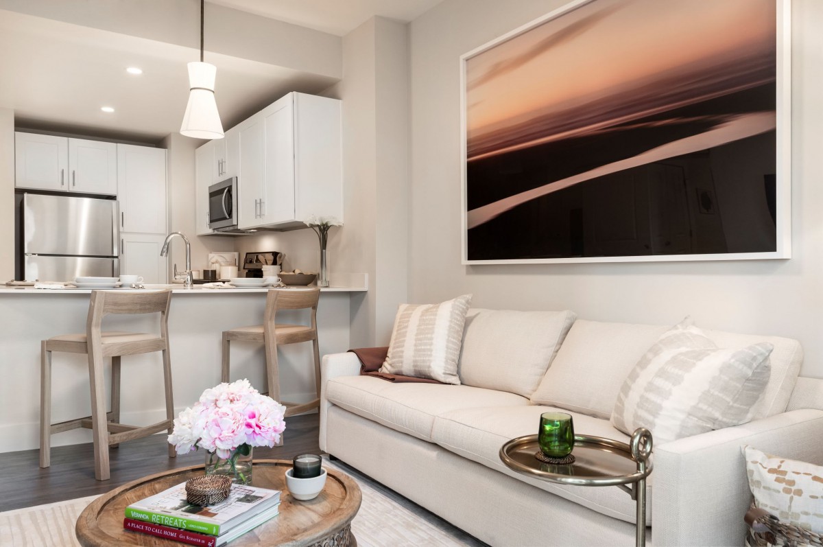 A modern living space with a cozy couch and kitchen area, featuring contemporary artwork and stylish decor.