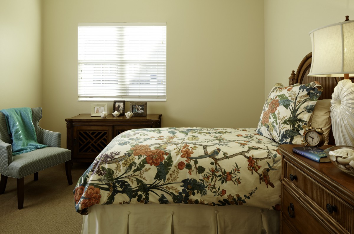 A cozy bedroom with floral bedding and a window letting in natural light.
