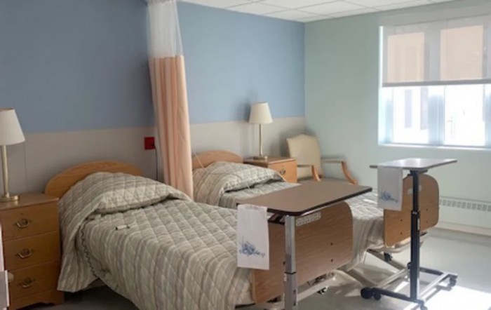 A clean and organized hospital room with two beds and medical equipment.