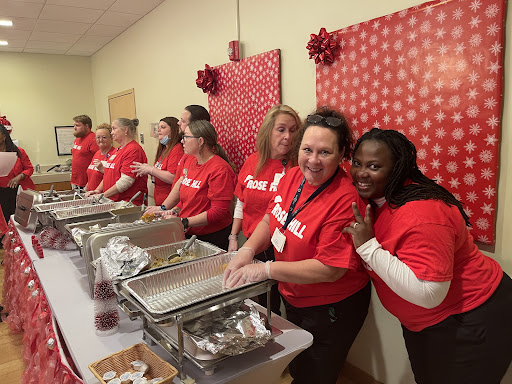 A group of volunteers in red shirts serving food at a community event.