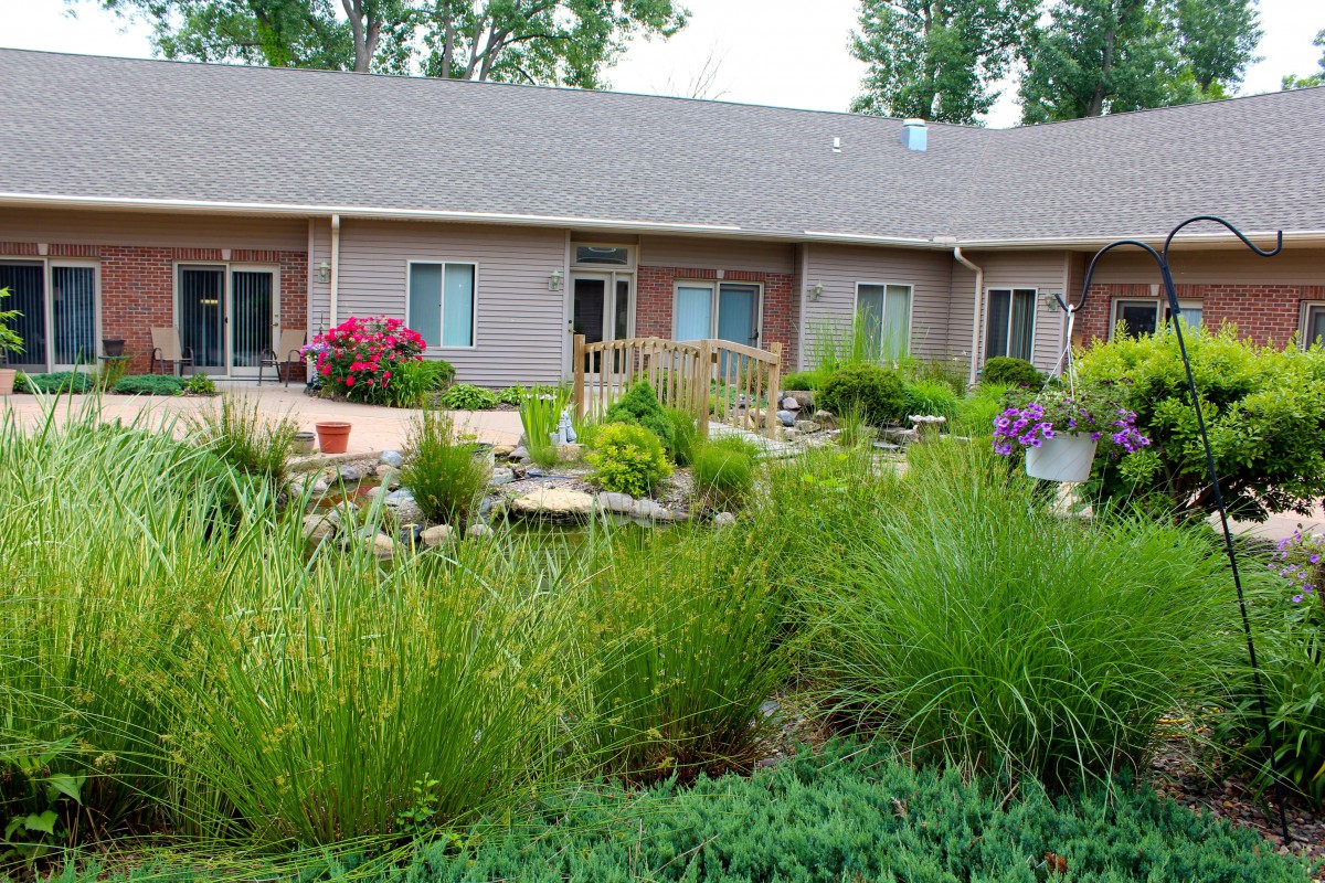 A beautiful garden in front of a house with various plants and flowers.