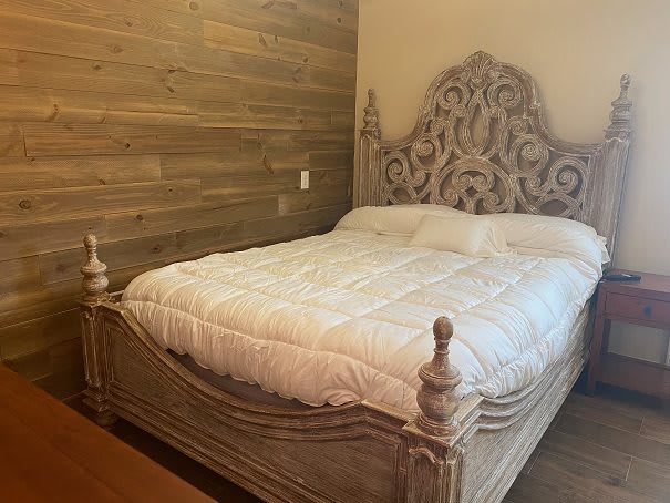 A bedroom with a decorative wooden bed and headboard.