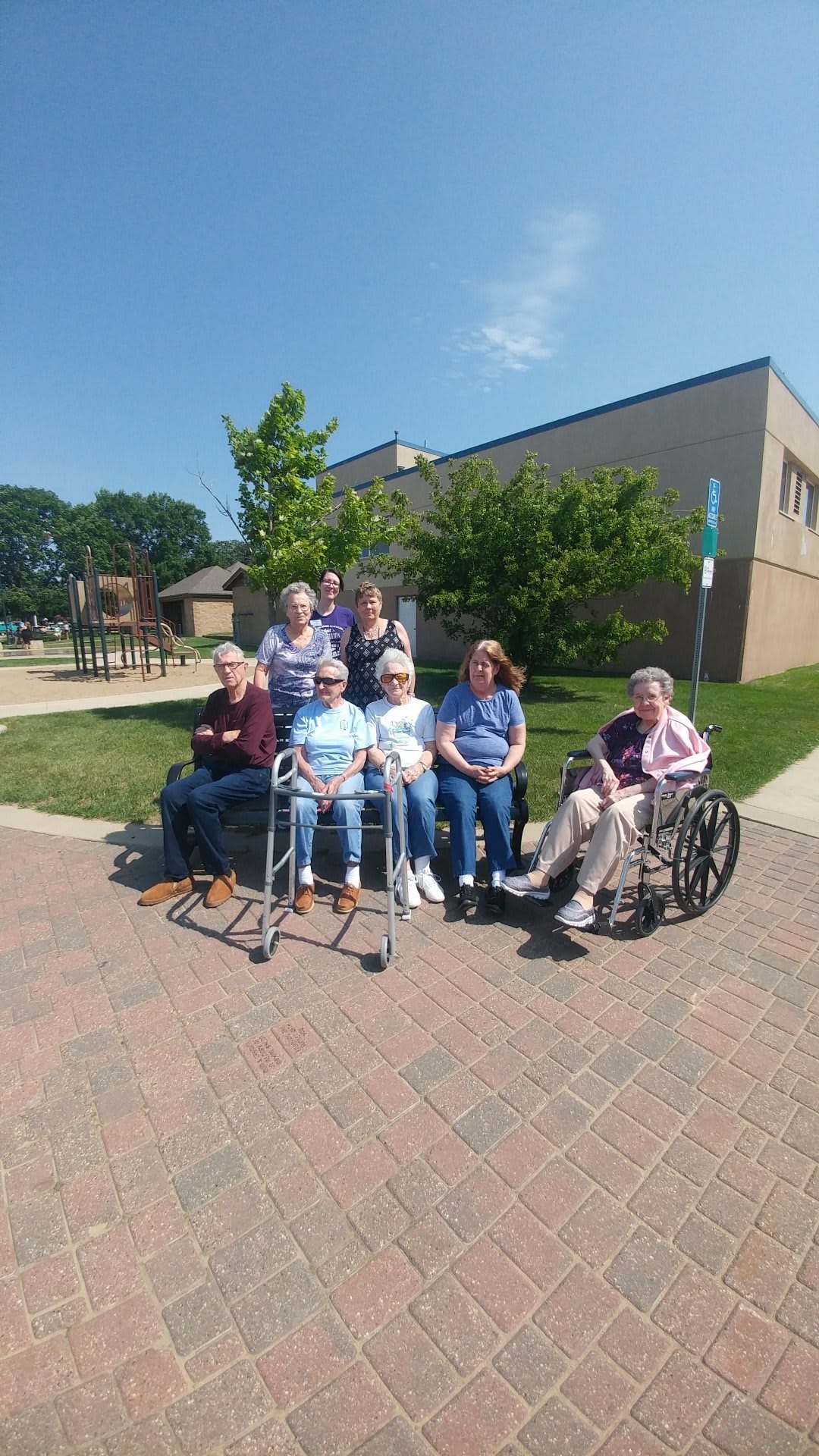 A group of seniors enjoying a sunny day outdoors near a building.