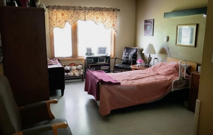 A hospital room with a bed, furniture, and a window with curtains.