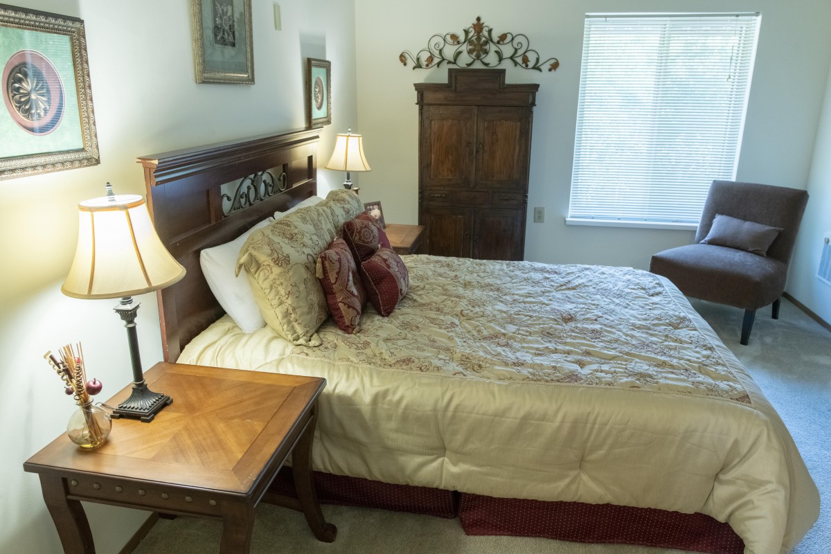 A cozy bedroom with a wooden bed, decorative pillows, and bedside lamps.