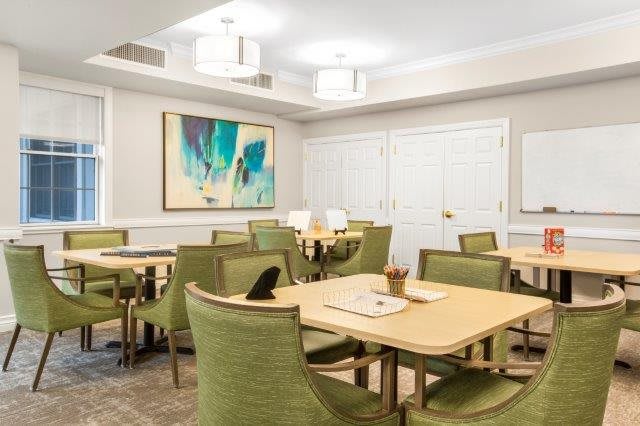 A modern dining area with green upholstered chairs and contemporary artwork.