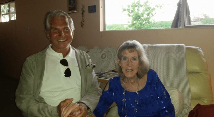 Two people sitting on a couch, smiling indoors.