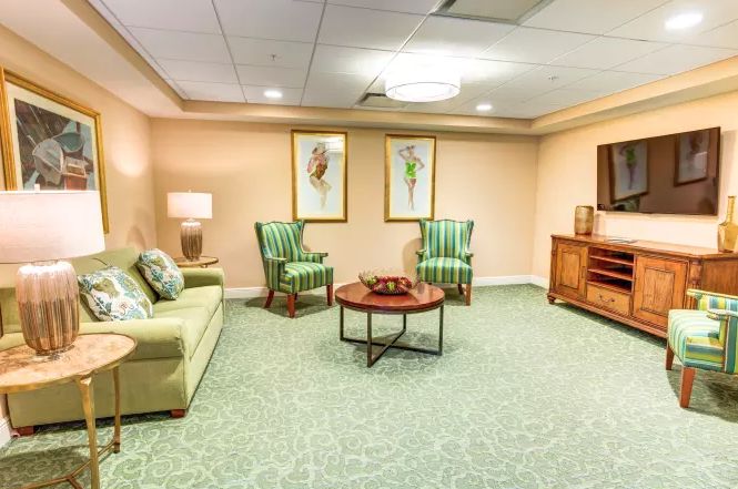 A cozy living room with a sofa, chairs, coffee table, and artwork on the walls.