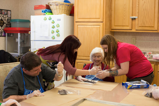 A group of individuals engaged in a fun cooking activity together in a cozy kitchen.