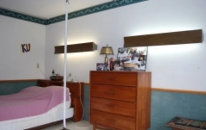 A bedroom featuring a wooden dresser with a lamp and mirror above it.