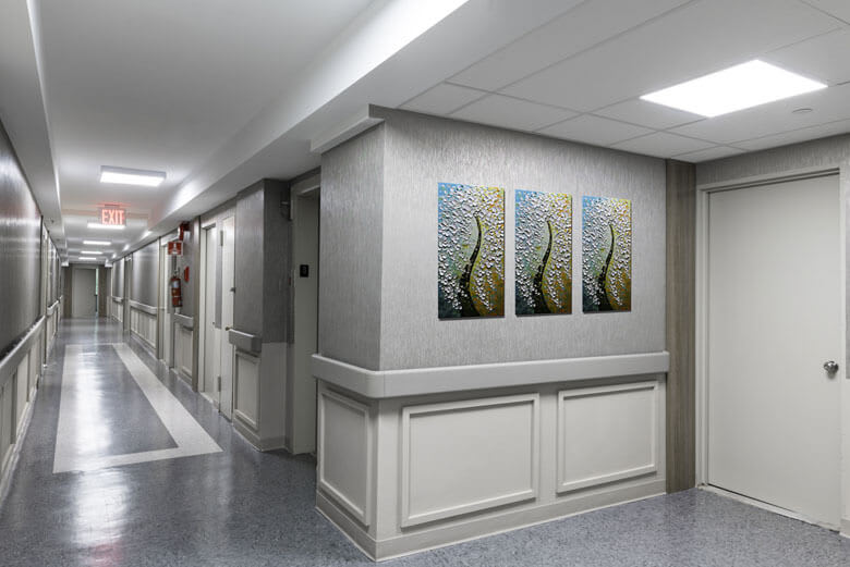 A clean and well-lit hospital corridor featuring art on the walls.