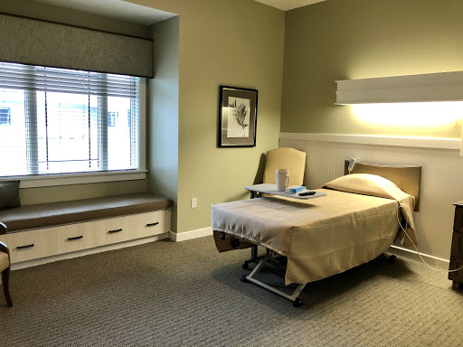A well-lit hospital room featuring a single bed, a window with a view, and minimalist decor.