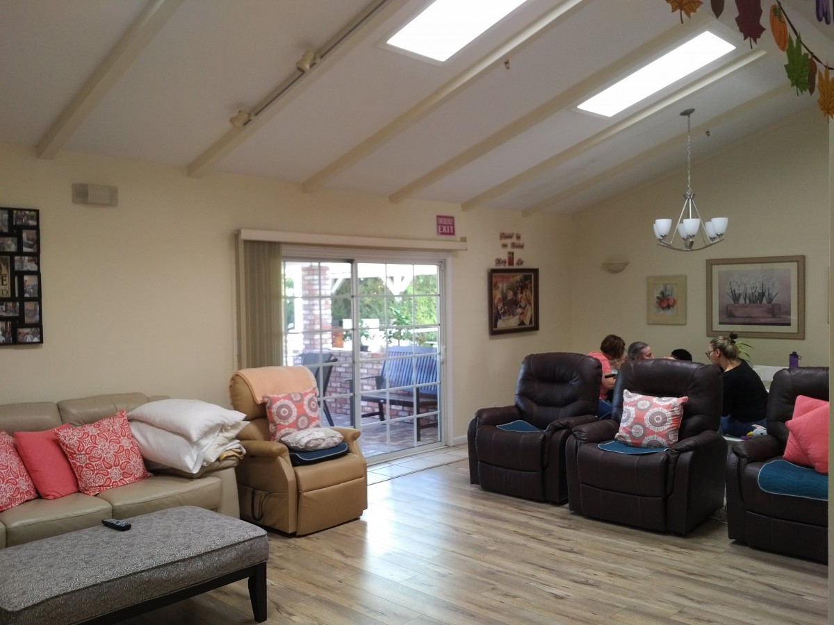 A cozy living room with recliners and couches, featuring skylights and a sliding door leading to an outdoor balcony.