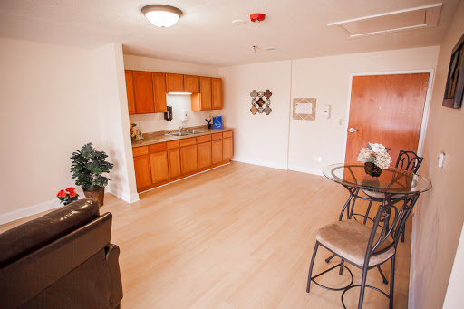 A modern kitchen and dining area featuring wooden cabinets, a small table, and cozy seating.