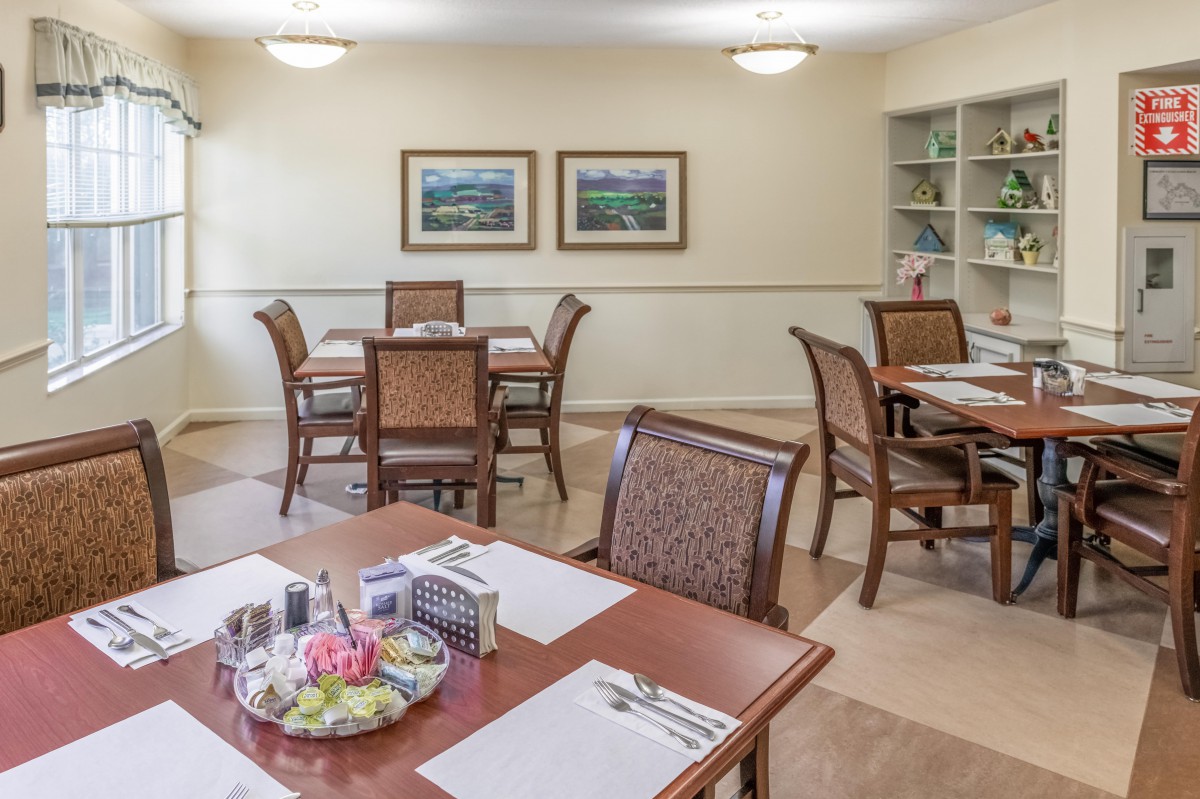 A cozy dining area with tables and chairs, decorated with framed artwork on the walls.