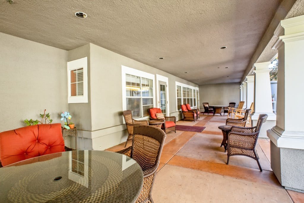 A spacious patio with wicker chairs and tables, decorated with colorful cushions and rugs.