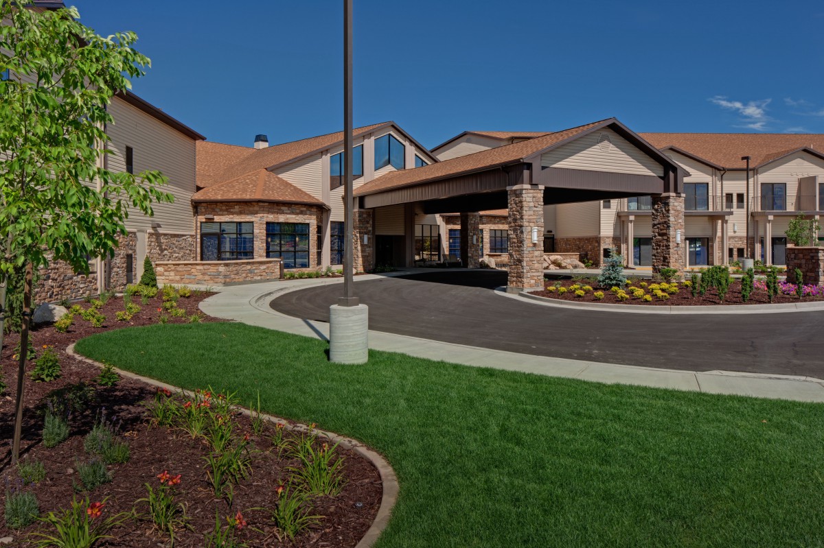 A modern residential building with a landscaped entrance and driveway.