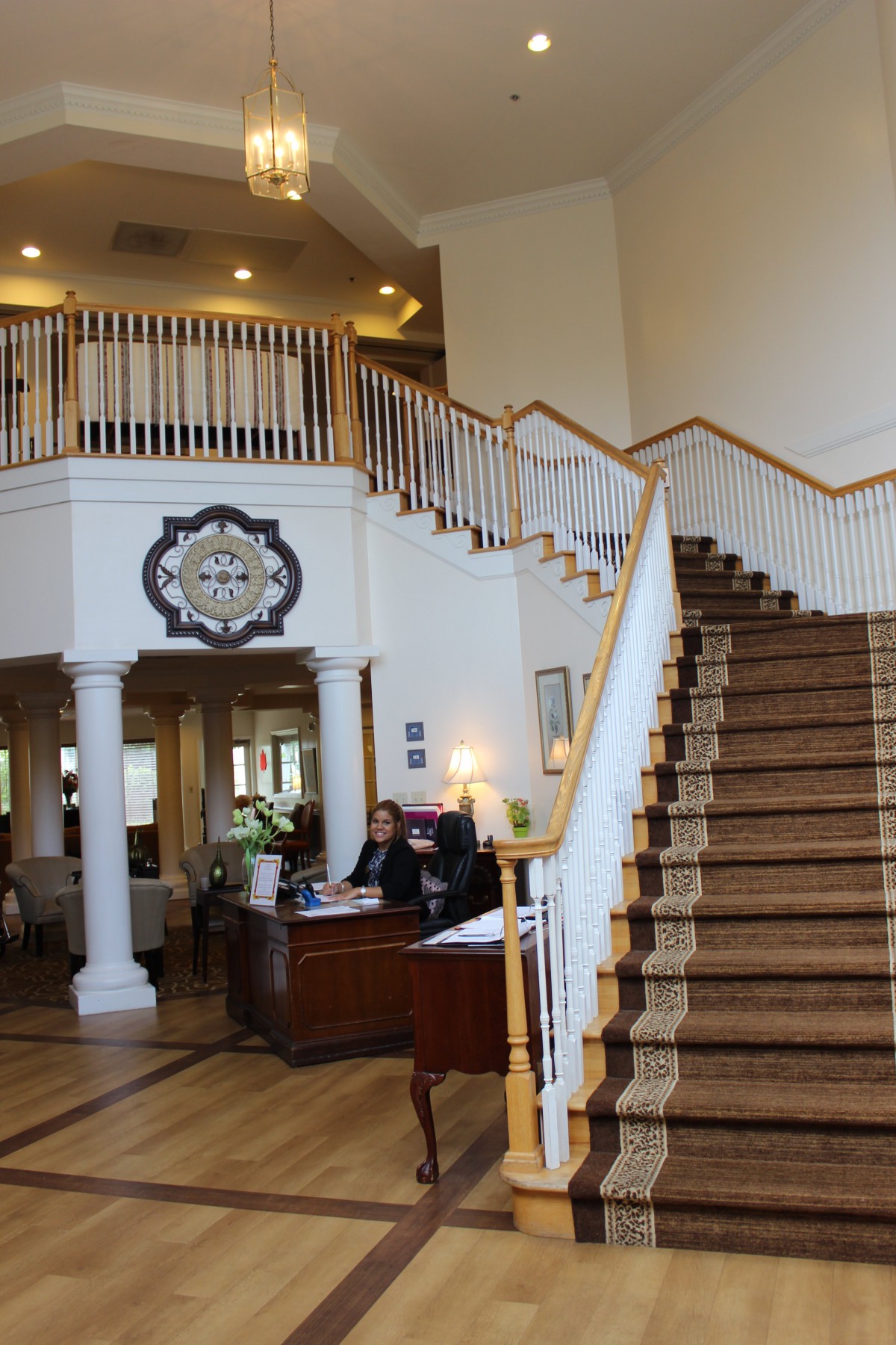 A spacious lobby with a grand staircase and a reception desk.