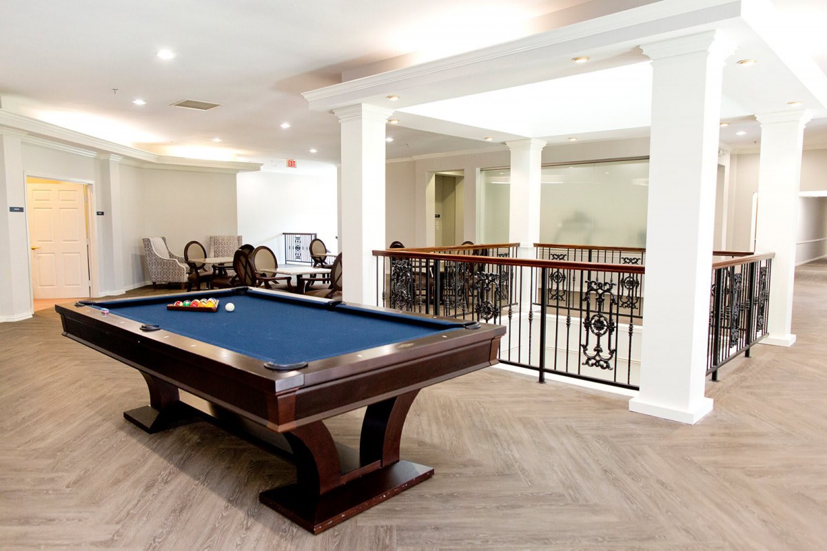 A modern recreation room featuring a billiards table with a blue felt surface and elegant wooden design.