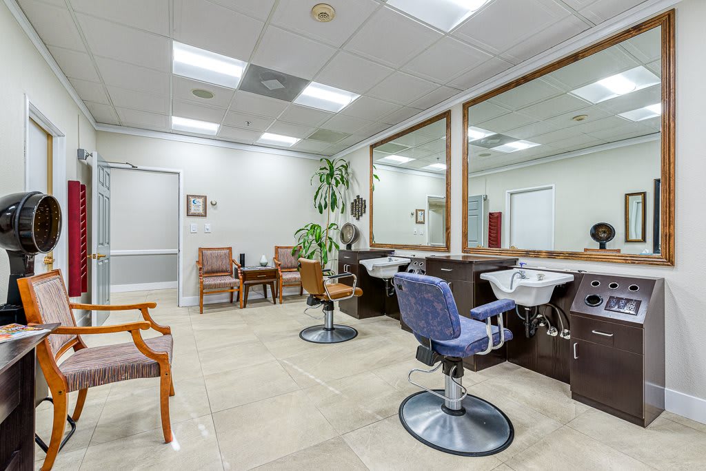 A tidy hair salon interior with barber chairs, large mirrors, and a comfortable waiting area.