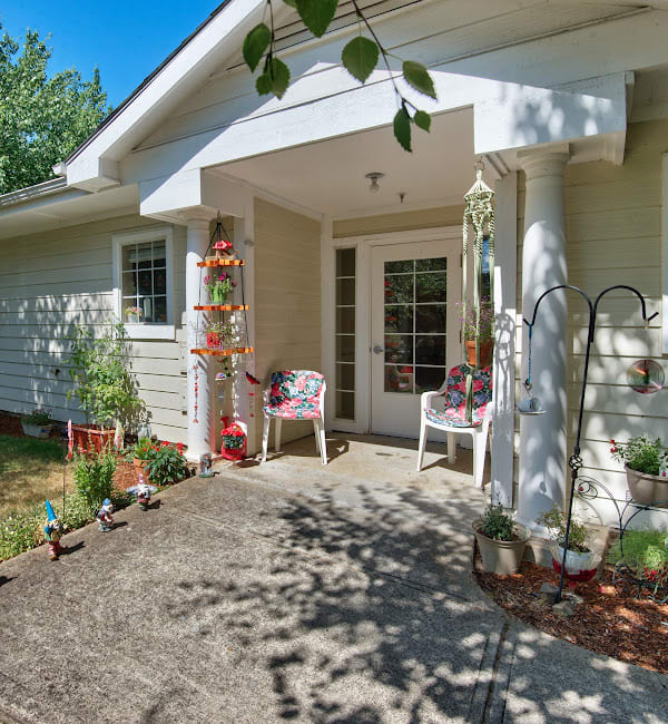 A cozy front porch with seating and decorative plants on a sunny day.