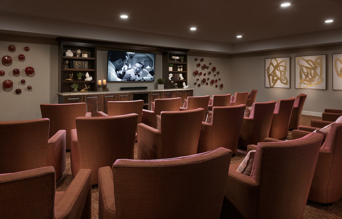 A cozy home theater with comfortable seating arranged in rows facing a large screen.