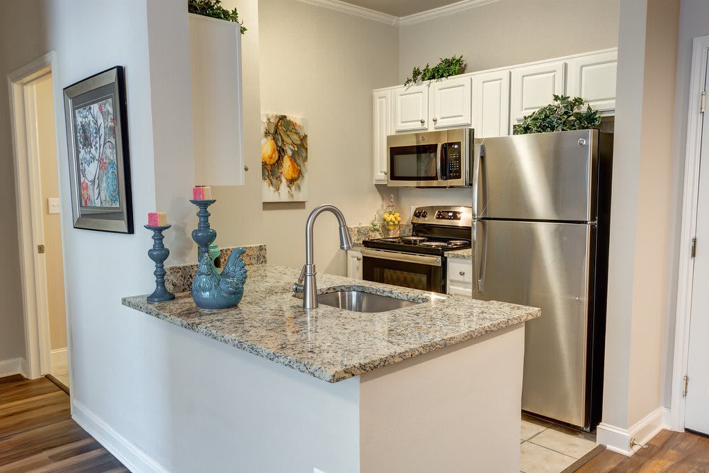 A modern kitchen featuring granite countertops and stainless steel appliances, accented with decorative candles.