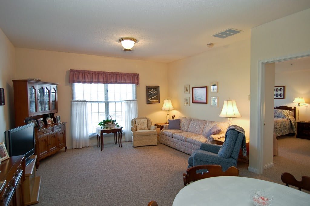 A cozy living room with a sofa, armchairs, and lamps creating a warm atmosphere.