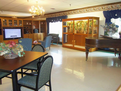 A spacious and elegantly furnished living room with a dining area, a grand piano, and a beautifully arranged wooden cabinet.