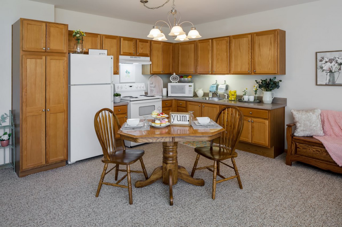 A cozy kitchen with wooden cabinets, a round dining table, and essential appliances.