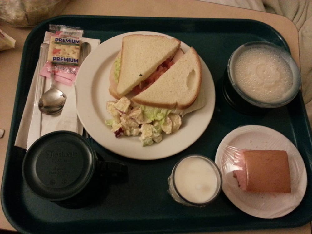 A meal tray with a sandwich, salad, and beverages.