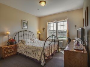 A cozy bedroom with a metal bed frame, floral bedding, and warm lighting.