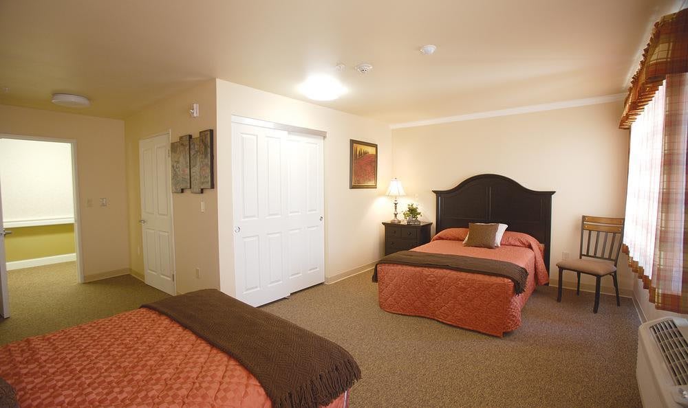A well-lit bedroom with two neatly made double beds, a nightstand, and decorative elements.