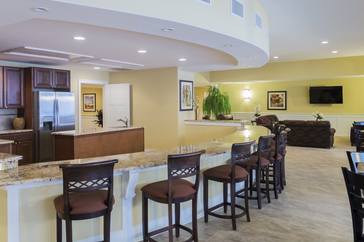 A modern kitchen and bar area with high stools and a curved countertop.