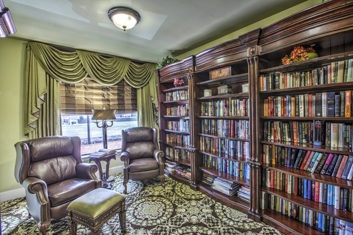 A cozy library with plush armchairs, lined with extensive bookshelves and a warm carpet.