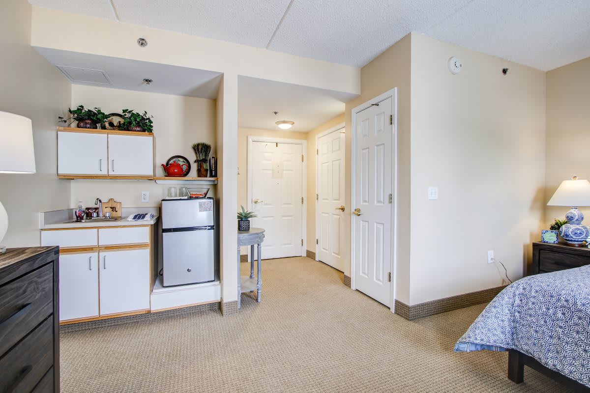A compact apartment with a kitchenette and hallway leading to multiple doors.