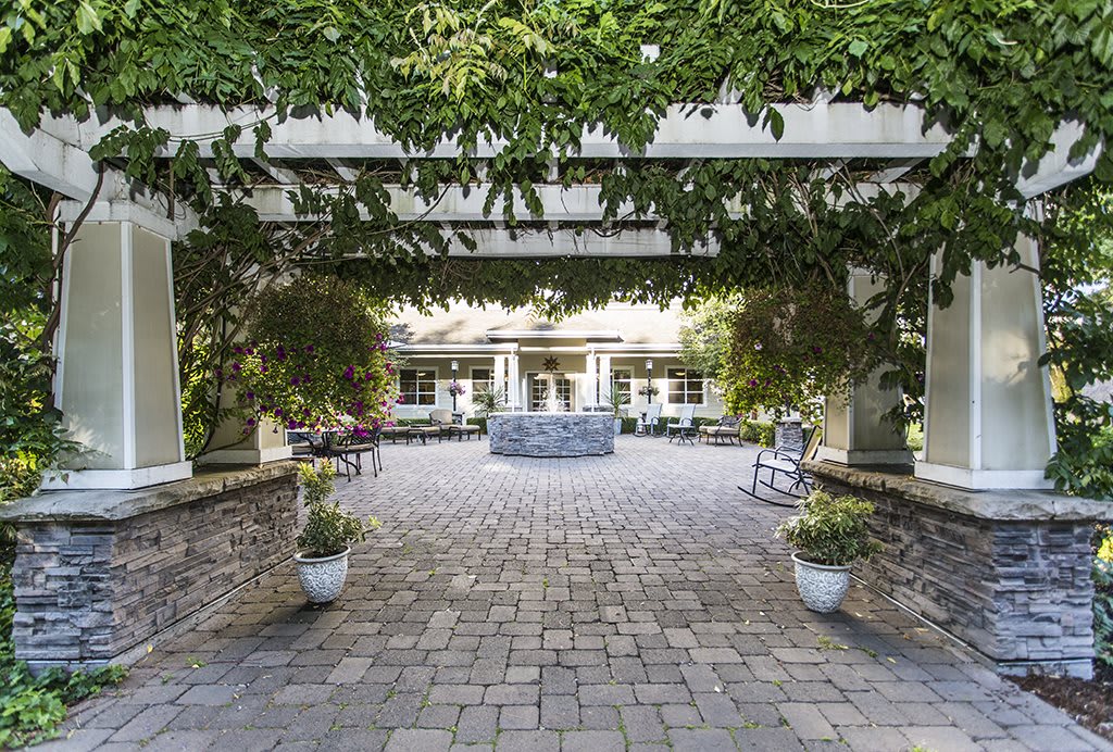 A serene courtyard featuring a central fountain surrounded by lush greenery and patio seating.