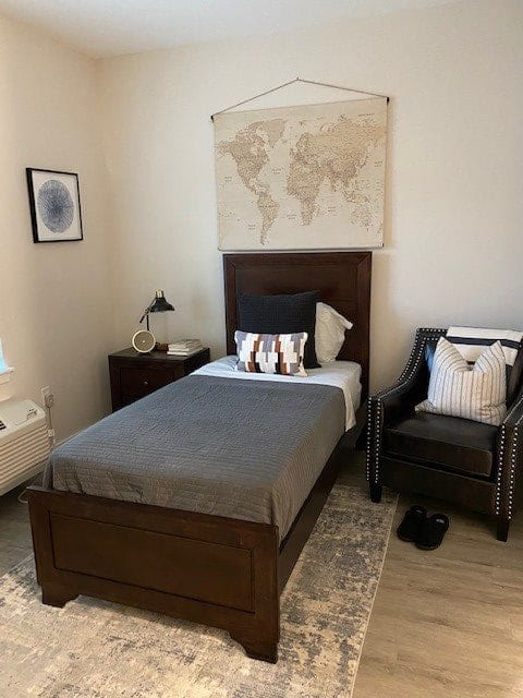 A cozy bedroom with a single bed, world map decor, and a comfortable chair.